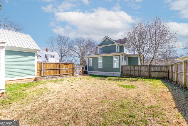 back of house featuring a fenced backyard and a yard