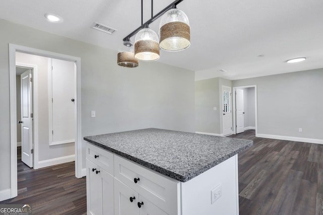 kitchen with baseboards, visible vents, dark wood finished floors, hanging light fixtures, and white cabinets