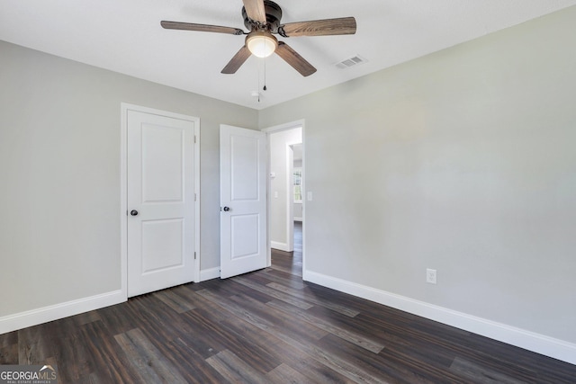 unfurnished bedroom with visible vents, baseboards, dark wood-style floors, and a ceiling fan