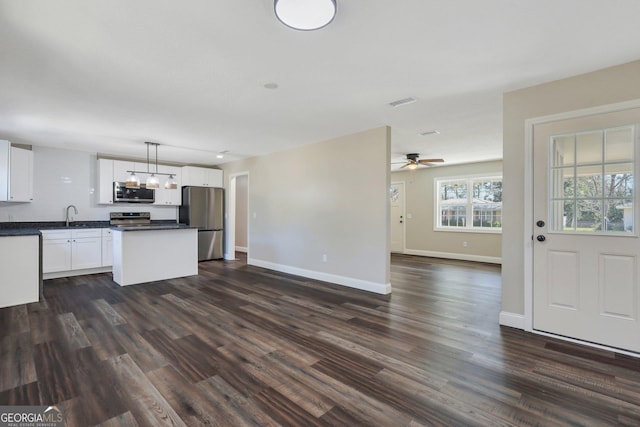 kitchen featuring a sink, stainless steel appliances, white cabinets, dark countertops, and open floor plan