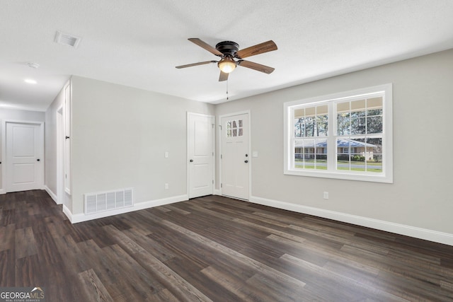 interior space with a ceiling fan, dark wood-type flooring, baseboards, and visible vents