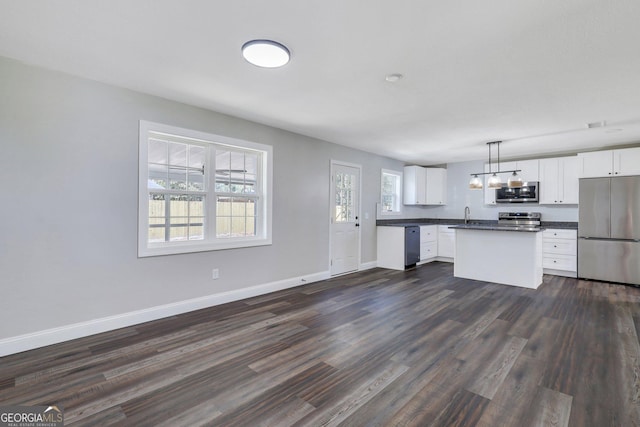 kitchen with dark countertops, baseboards, appliances with stainless steel finishes, dark wood-style floors, and white cabinets