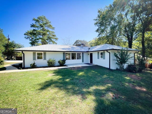 view of front facade with a front lawn, stucco siding, a carport, and metal roof