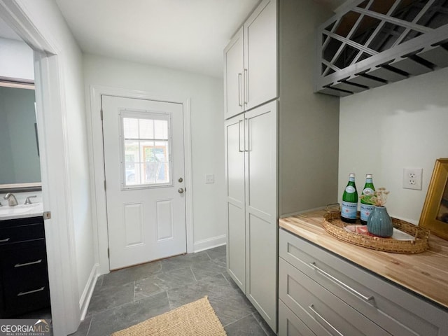 interior space with a sink, stone finish flooring, baseboards, and a dry bar