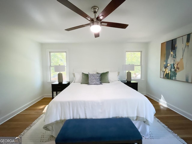 bedroom with multiple windows, wood finished floors, and baseboards