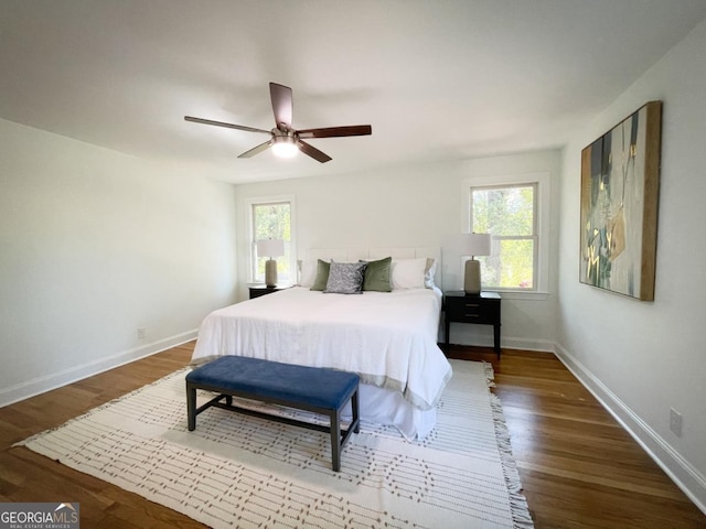 bedroom featuring multiple windows, baseboards, and wood finished floors