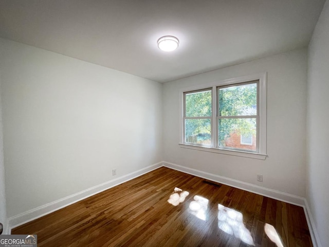 unfurnished room with baseboards and dark wood-style flooring