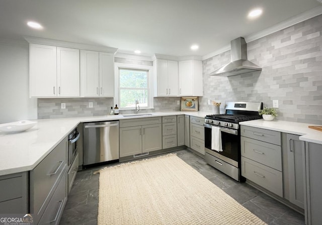 kitchen featuring a sink, stainless steel appliances, ornamental molding, and wall chimney range hood