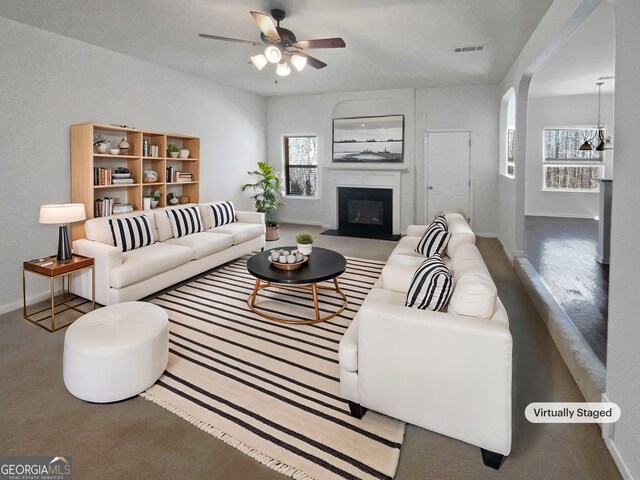 living area with visible vents, baseboards, a glass covered fireplace, and a ceiling fan