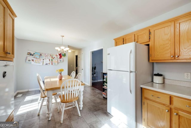 kitchen featuring baseboards, freestanding refrigerator, light countertops, fridge, and a notable chandelier