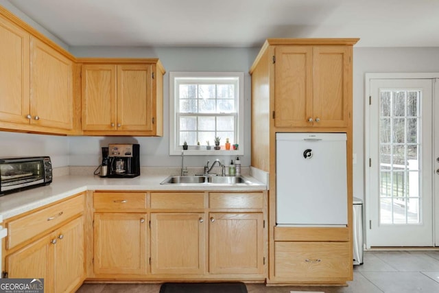 kitchen featuring a toaster, light brown cabinets, and a sink