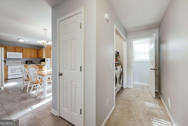 hallway featuring a chandelier, light tile patterned floors, baseboards, and separate washer and dryer