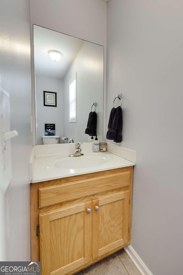 half bath with toilet, vanity, and tile patterned flooring