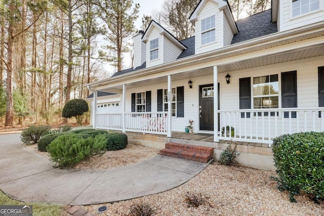 view of front of house featuring a porch, a shingled roof, and a garage