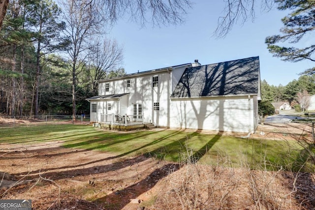 back of house with a yard, fence, roof with shingles, and a wooden deck