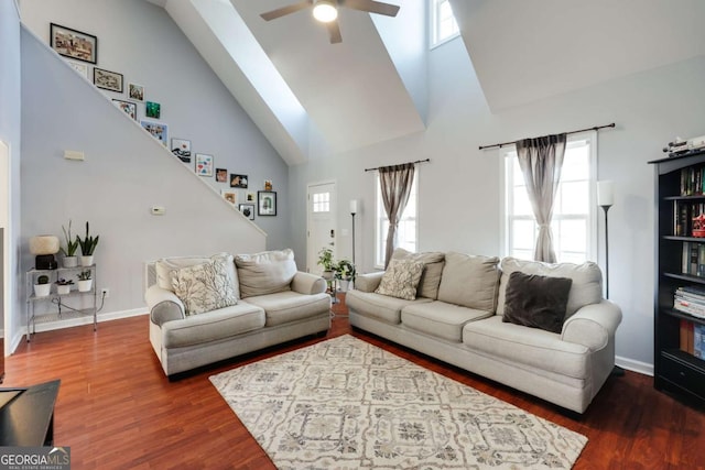 living area with a healthy amount of sunlight, high vaulted ceiling, baseboards, and wood finished floors