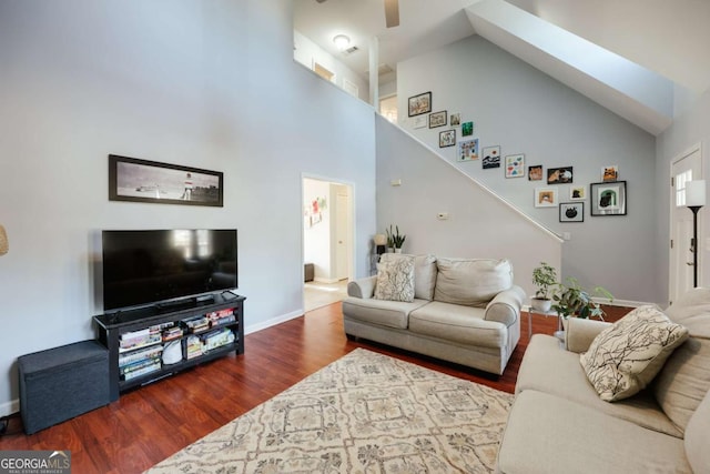 living room featuring baseboards, high vaulted ceiling, ceiling fan, and wood finished floors