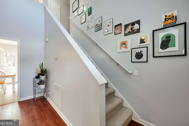 staircase with visible vents, baseboards, and wood finished floors