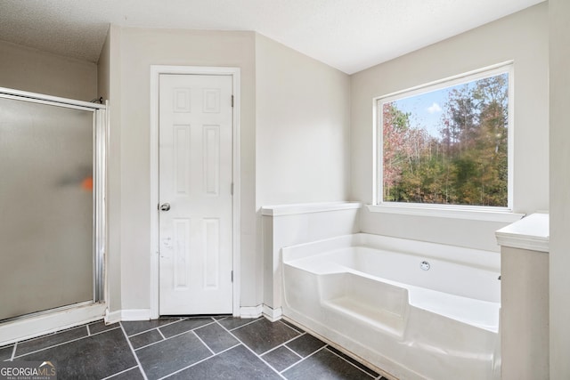 full bath with baseboards, a garden tub, a shower stall, and a textured ceiling