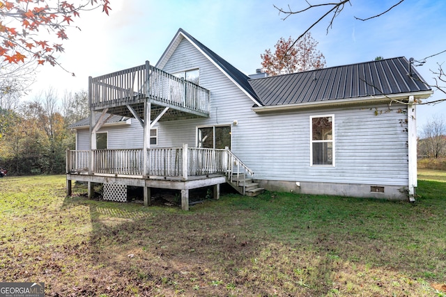 rear view of property with crawl space, a wooden deck, a lawn, and metal roof