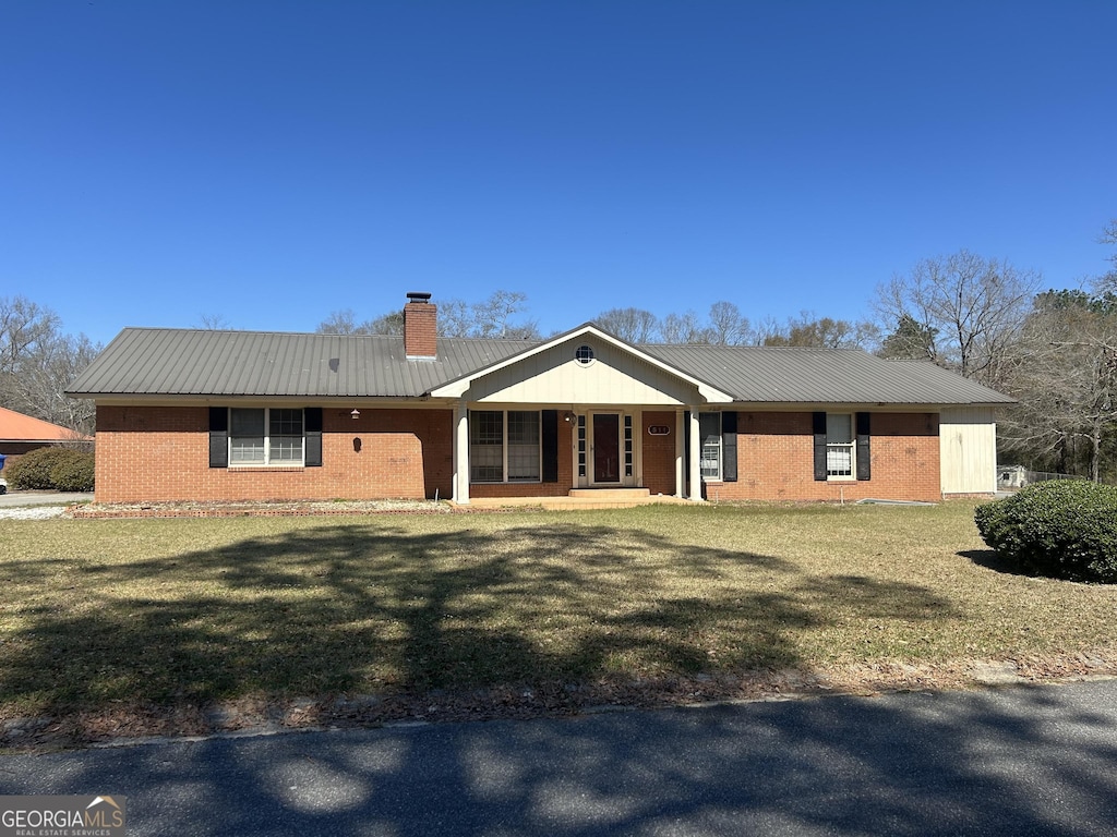 ranch-style home with a chimney, a front lawn, and metal roof