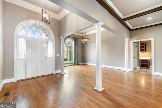 foyer with a chandelier, baseboards, light wood-style flooring, and ornate columns