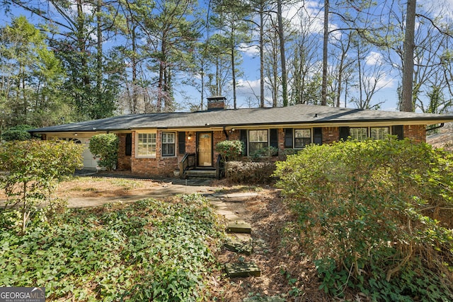 ranch-style home with a garage, brick siding, and a chimney