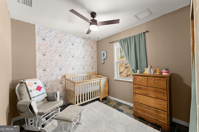 bedroom with visible vents, baseboards, a crib, and stone finish floor