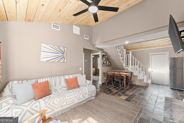 living room with stairs, wooden ceiling, visible vents, and stone tile flooring