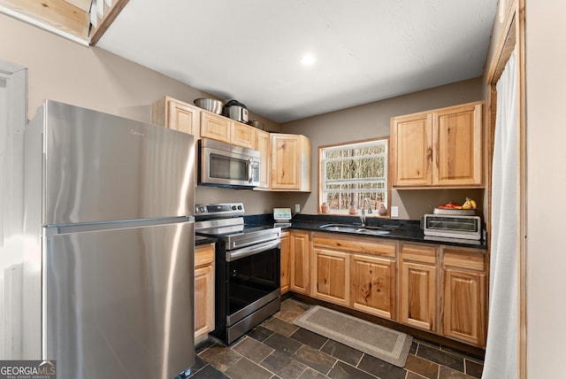 kitchen with light brown cabinets, a toaster, a sink, appliances with stainless steel finishes, and dark countertops