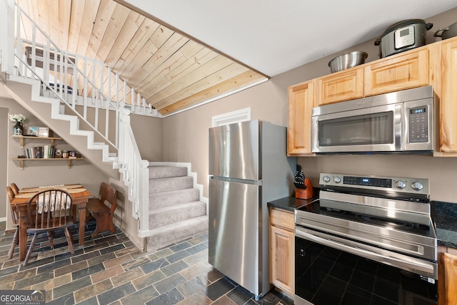 kitchen with wood ceiling, dark countertops, appliances with stainless steel finishes, and light brown cabinetry