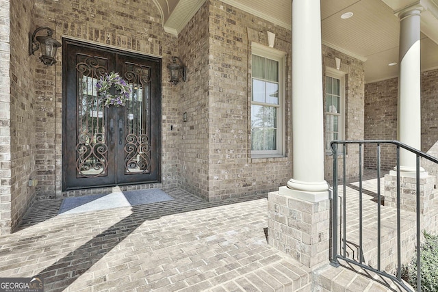 doorway to property with brick siding, a porch, and french doors