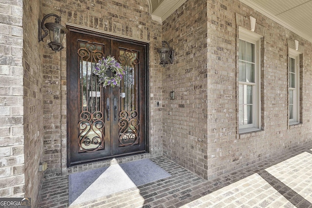 entrance to property with covered porch, french doors, and brick siding