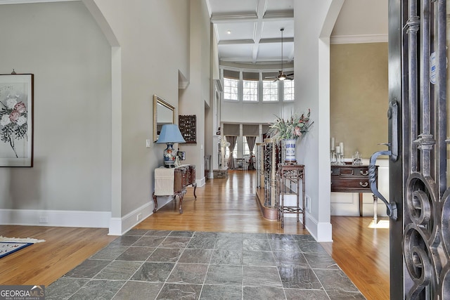 foyer entrance featuring a high ceiling, wood finished floors, arched walkways, coffered ceiling, and a ceiling fan