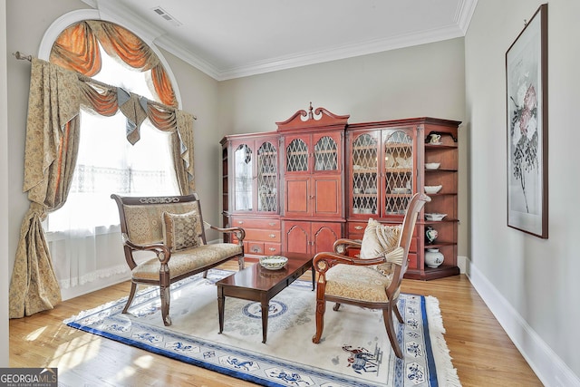 sitting room featuring visible vents, crown molding, light wood-type flooring, and baseboards