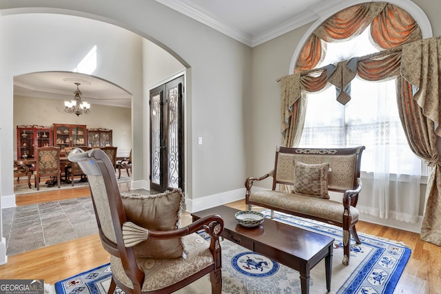 living area with arched walkways, a notable chandelier, wood finished floors, and crown molding