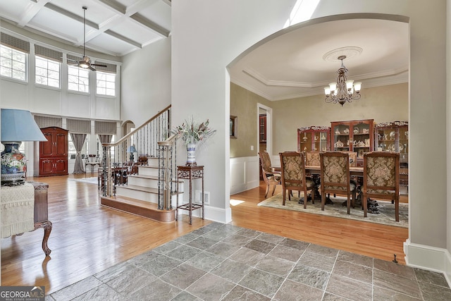 interior space featuring wood finished floors, coffered ceiling, arched walkways, beamed ceiling, and ceiling fan with notable chandelier