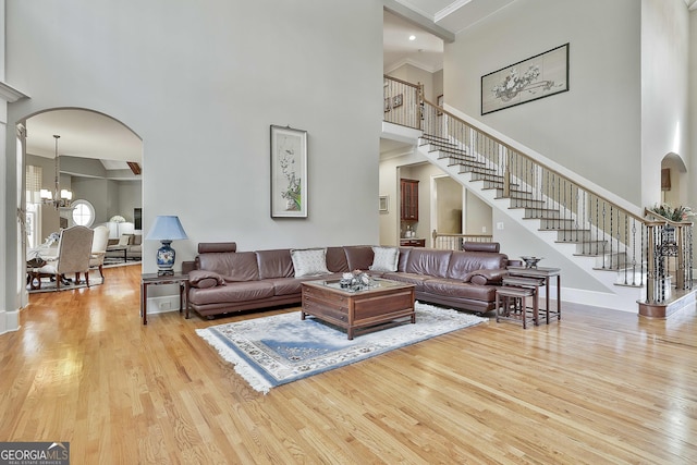 living room with stairs, an inviting chandelier, wood finished floors, and arched walkways