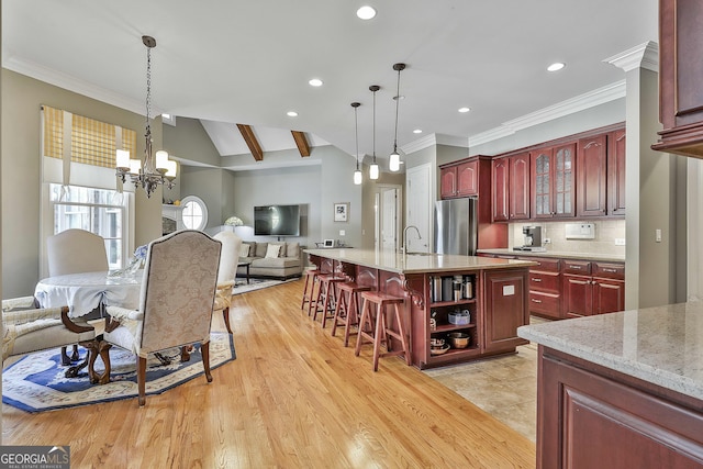 kitchen featuring freestanding refrigerator, a sink, dark brown cabinets, a notable chandelier, and open floor plan