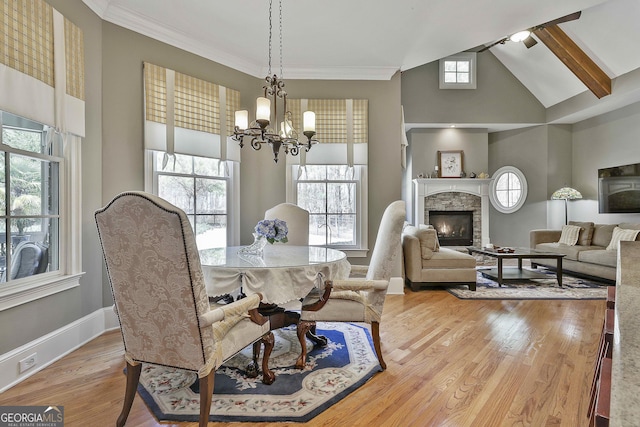 dining space with a stone fireplace, an inviting chandelier, wood finished floors, and a healthy amount of sunlight