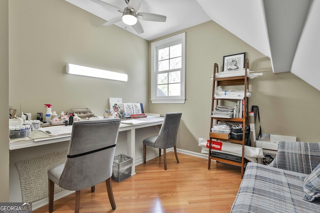 office space featuring a ceiling fan, baseboards, built in study area, lofted ceiling, and light wood-type flooring