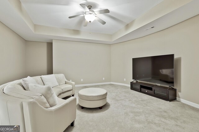 carpeted living area featuring visible vents, ceiling fan, a raised ceiling, and baseboards