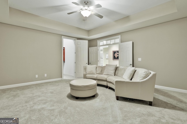 carpeted living area with baseboards and ceiling fan