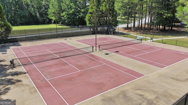 view of tennis court featuring community basketball court and fence