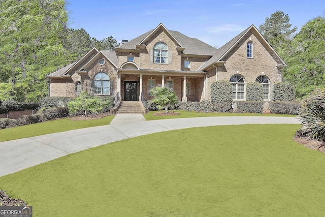 view of front of property featuring brick siding, driveway, and a front yard