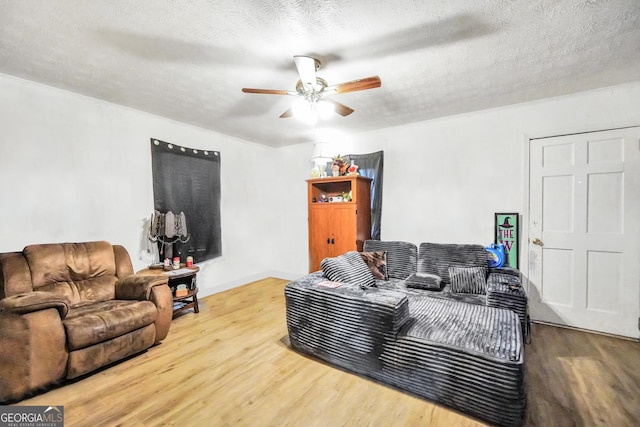 living room with a textured ceiling, a ceiling fan, and wood finished floors