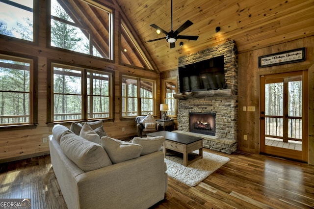 living area with a stone fireplace, wood walls, wood ceiling, and hardwood / wood-style floors