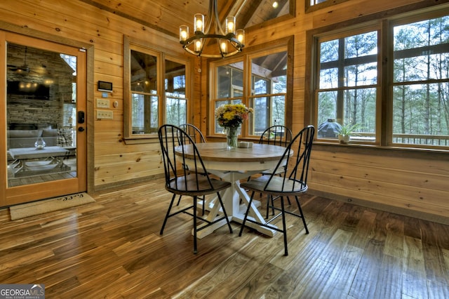 dining room featuring wooden walls, a notable chandelier, and dark wood-style floors