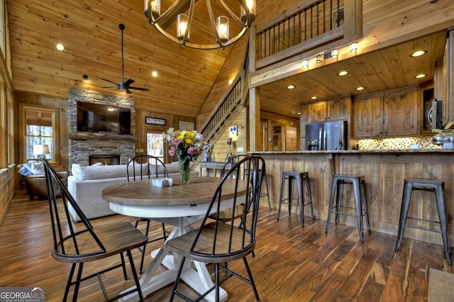 dining space with wood ceiling, plenty of natural light, dark wood-type flooring, and a stone fireplace