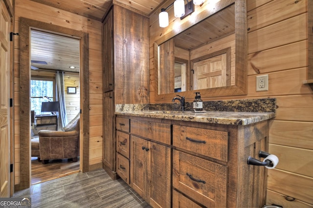 bathroom with wooden walls, wooden ceiling, vanity, and wood finished floors